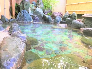 Una piscina cristalina con rocas grandes y una valla de bambú al fondo.