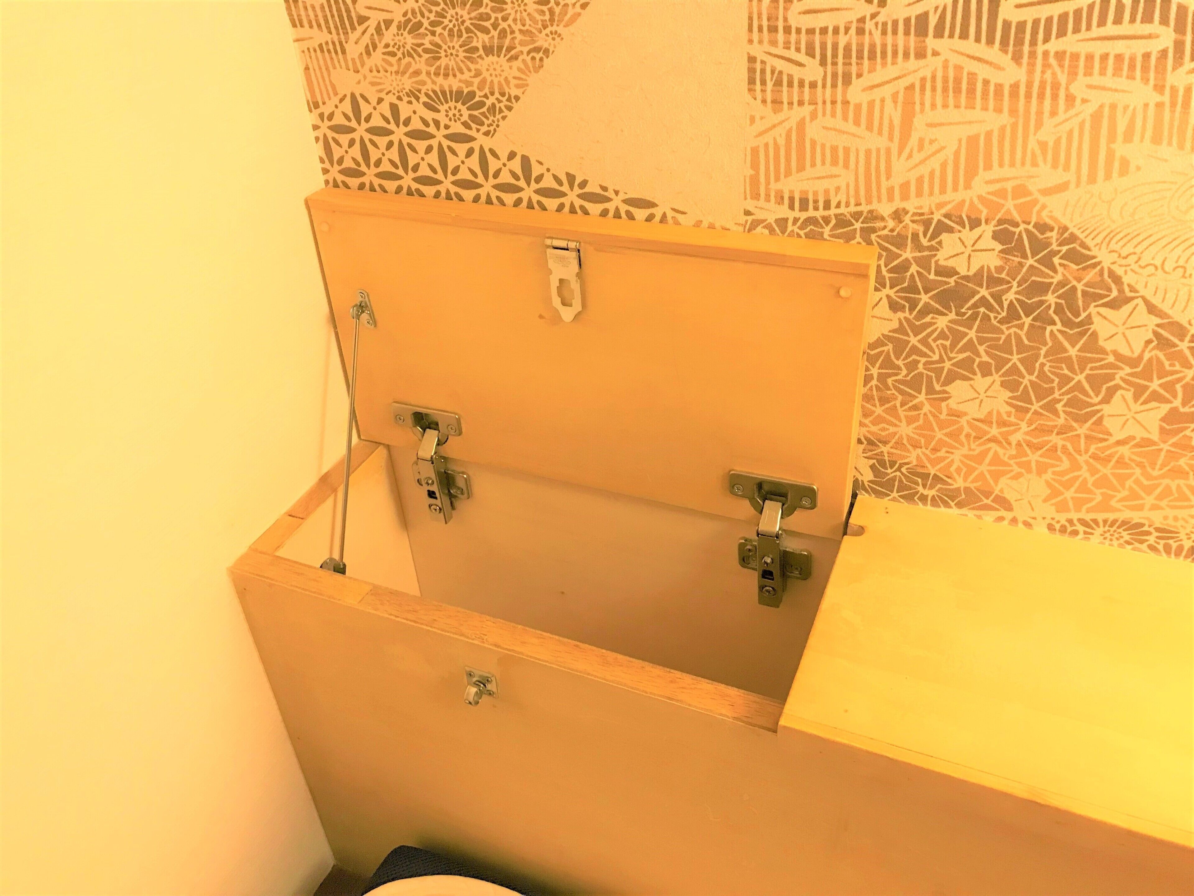 A wooden cabinet with a hinged door, a metal latch, and a small shelf.
