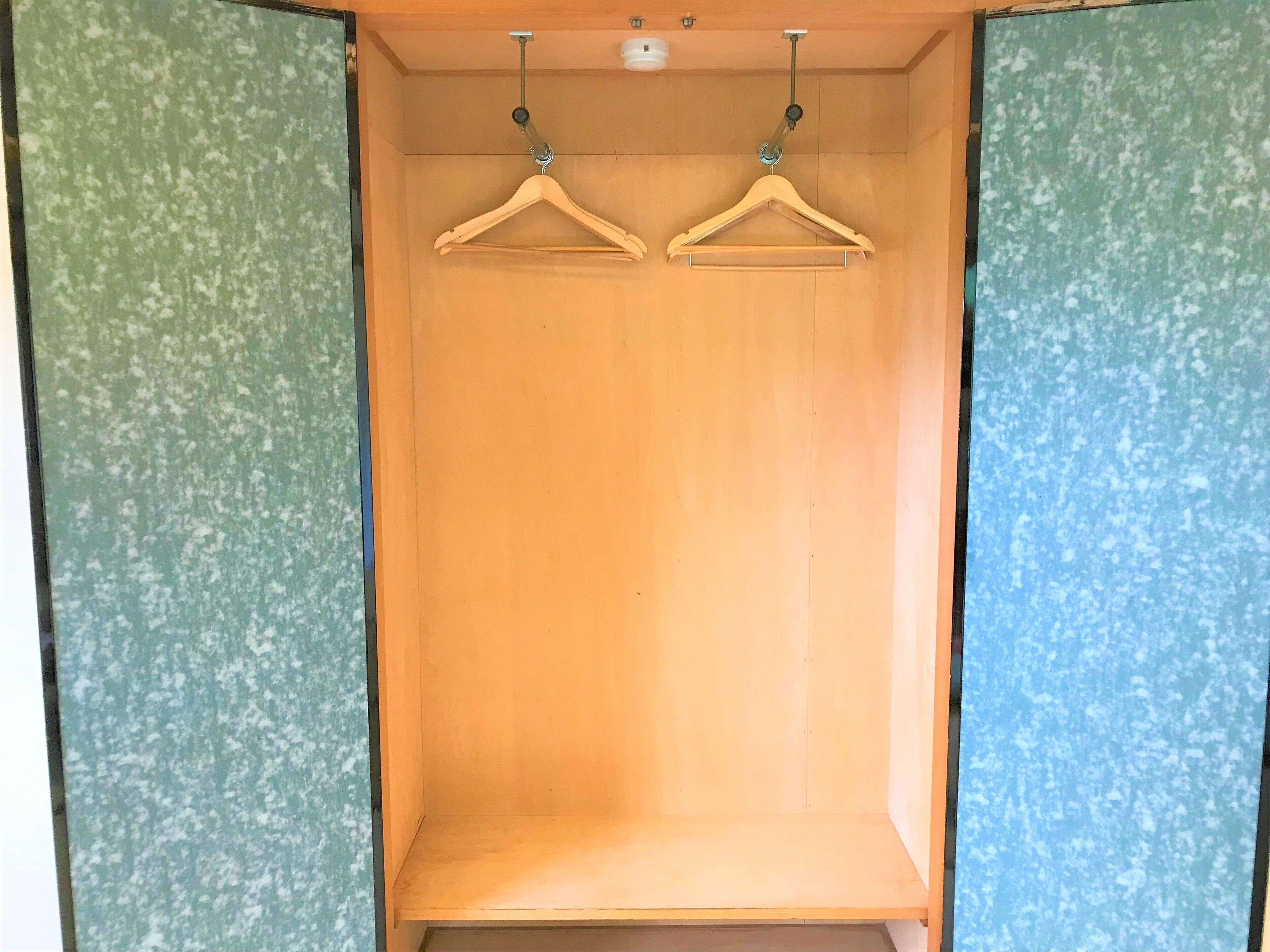 A wooden wardrobe with two wooden hangers.