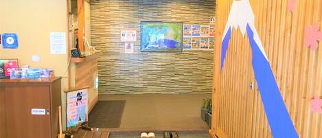 Una zona de recepción con un mostrador de madera, un mapa en la pared y un par de zapatos en el suelo.