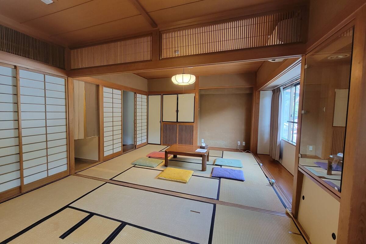 Una habitación japonesa tradicional con suelo de tatami, puertas correderas y bajo techo de madera.