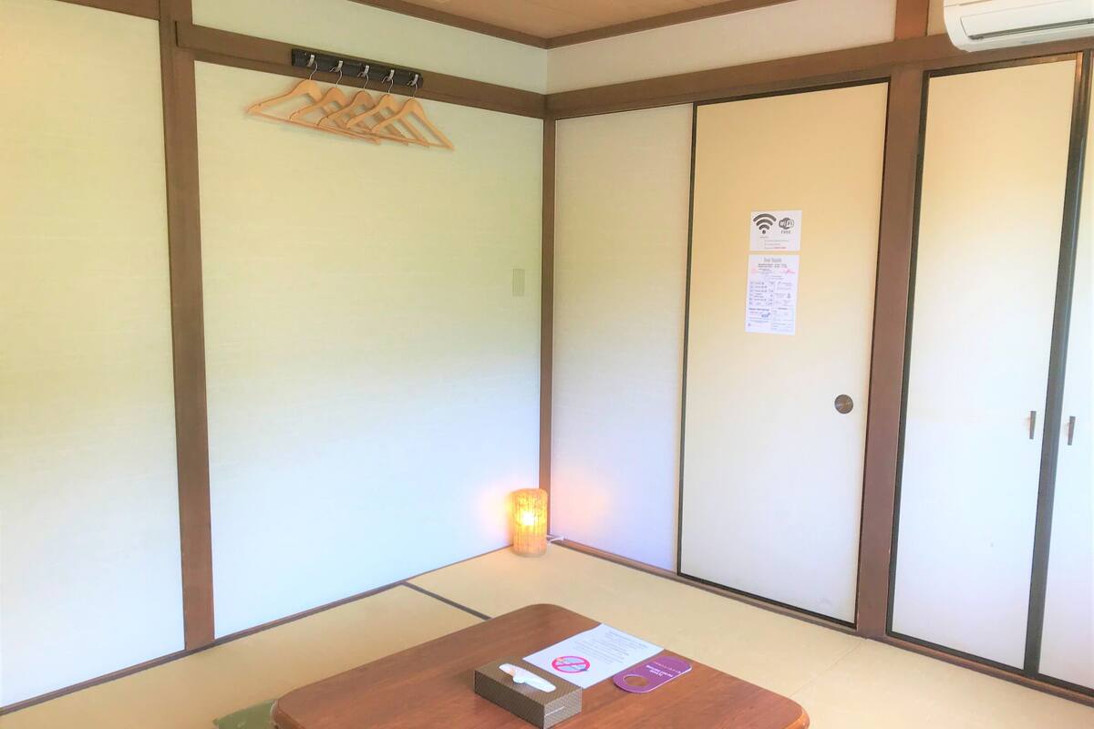 Una habitación japonesa tradicional con suelo de tatami, una mesa de madera y un perchero.