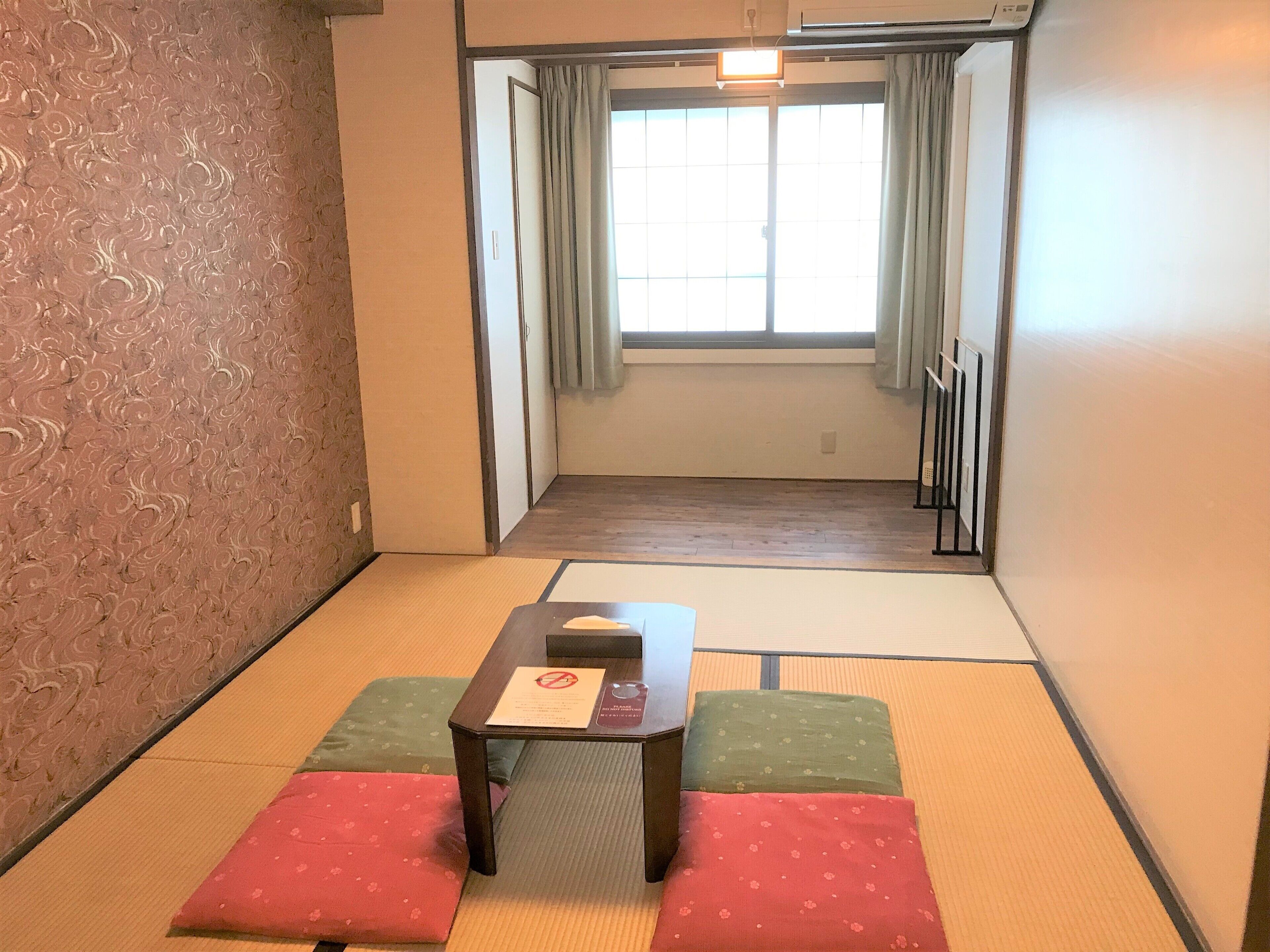 Una habitación japonesa tradicional con suelo de tatami, una mesa baja y cojines.