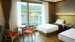 A hotel room with a balcony, a bed, a desk with a telephone, a chair, and a small table. - Arisu Gyeongju (Gyeongju)