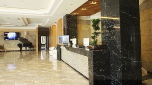 A lobby with a reception desk, a piano, a television, and a plant. - Arisu Gyeongju (Gyeongju)