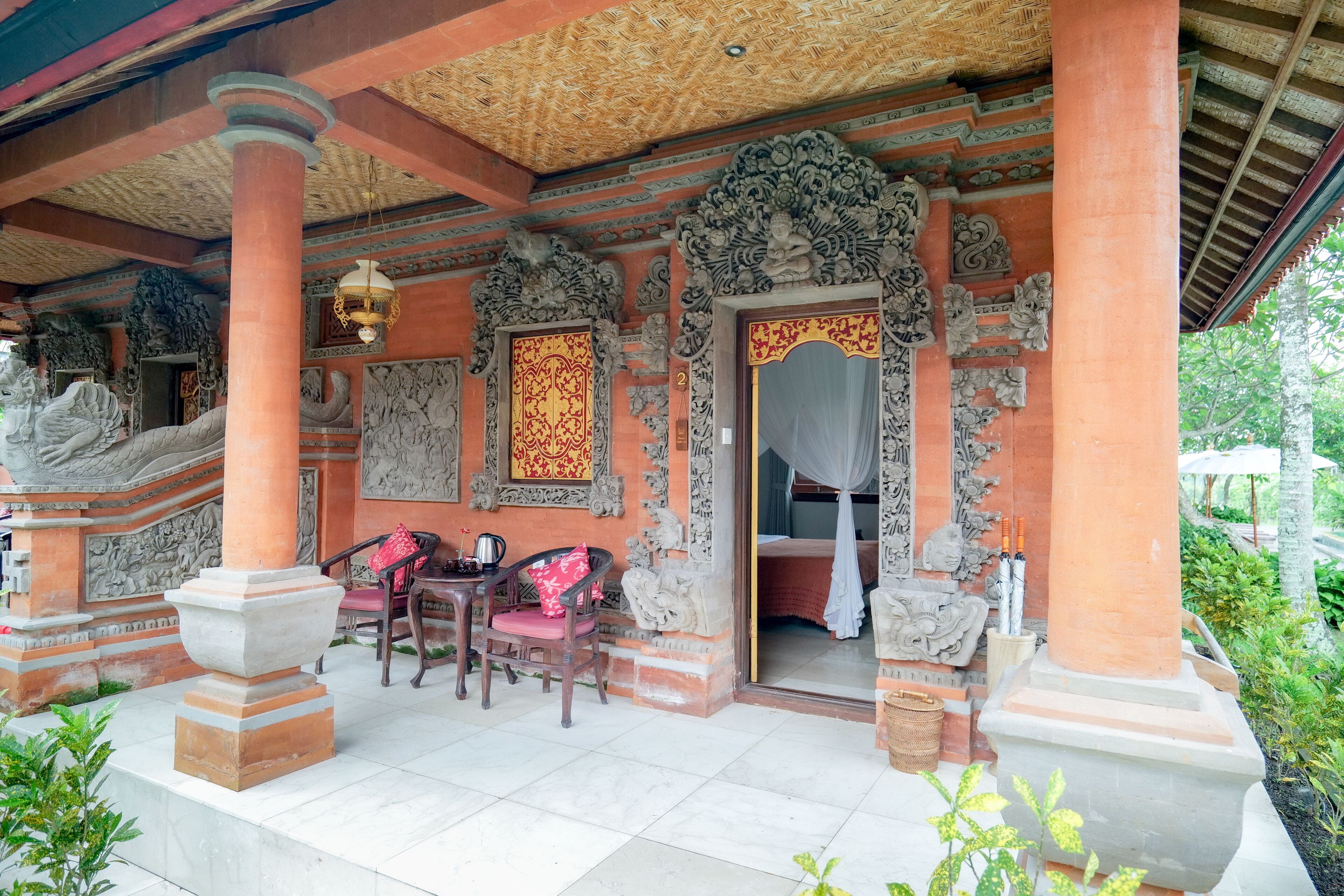A traditional building with ornate carvings, a covered porch, and a seating area with chairs.