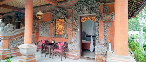 A traditional building with ornate carvings, a covered porch, and a seating area with chairs.