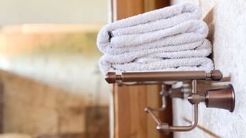 A towel rack with neatly folded towels against a textured wall.