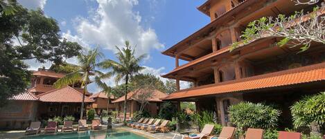 A pool area with lounge chairs and a building with a tiled roof.
