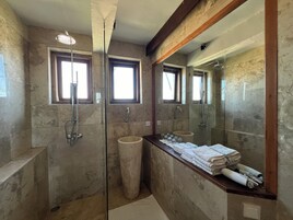 A bathroom with a glass-enclosed shower, a sink with a marble countertop, and a large mirror.