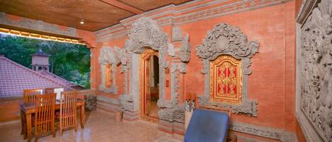 A room with a blue reclining chair, a wooden table with chairs, and ornate stone carvings on the walls.