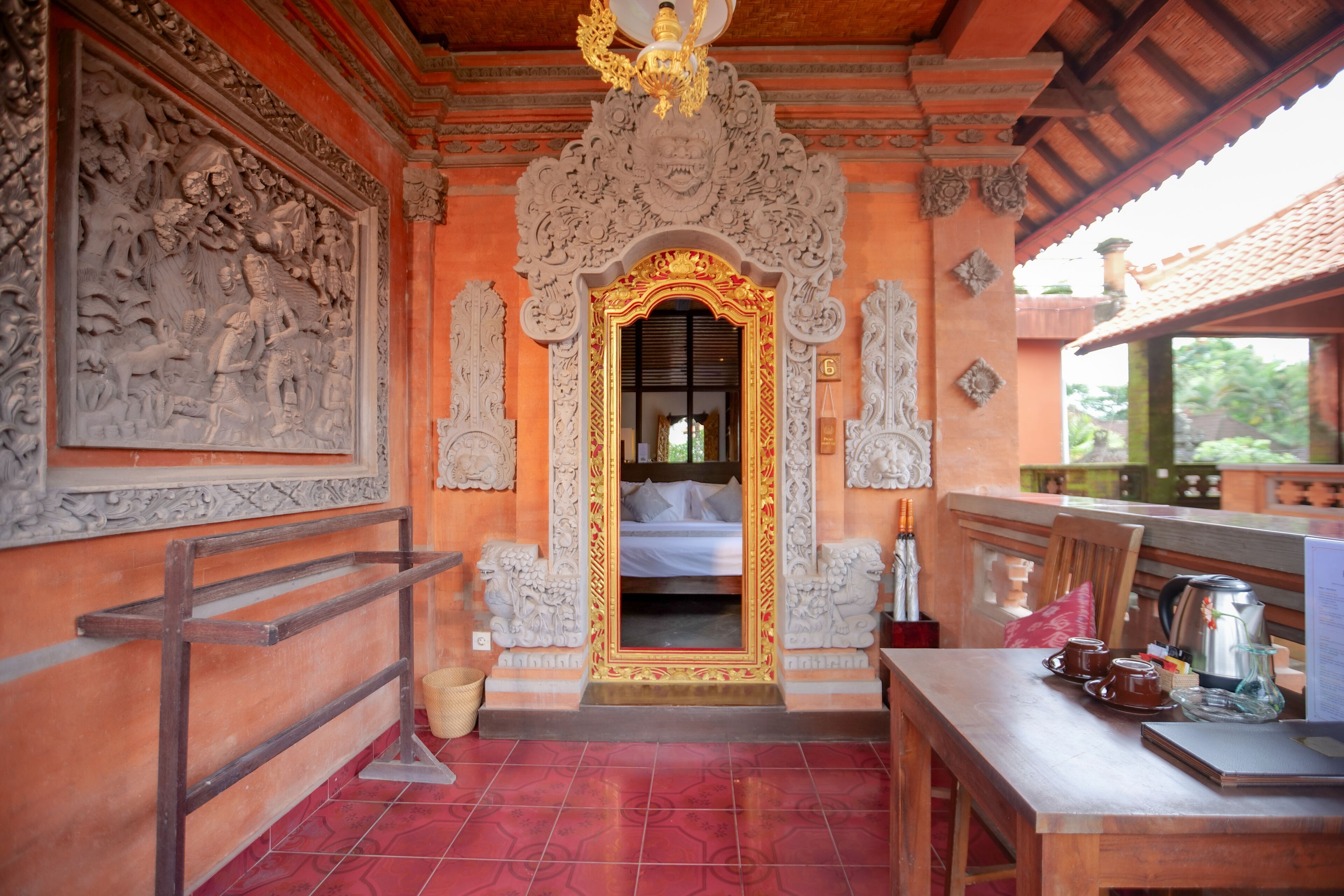 Una habitación tradicional con cama, una mesa con juego de té y elaboradas tallas en las paredes.