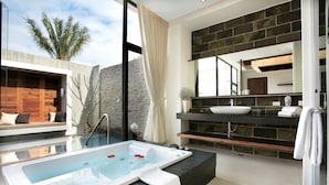 A modern bathroom with a large bathtub, a stone wall, and a large mirror. - H Villa (Tainan)