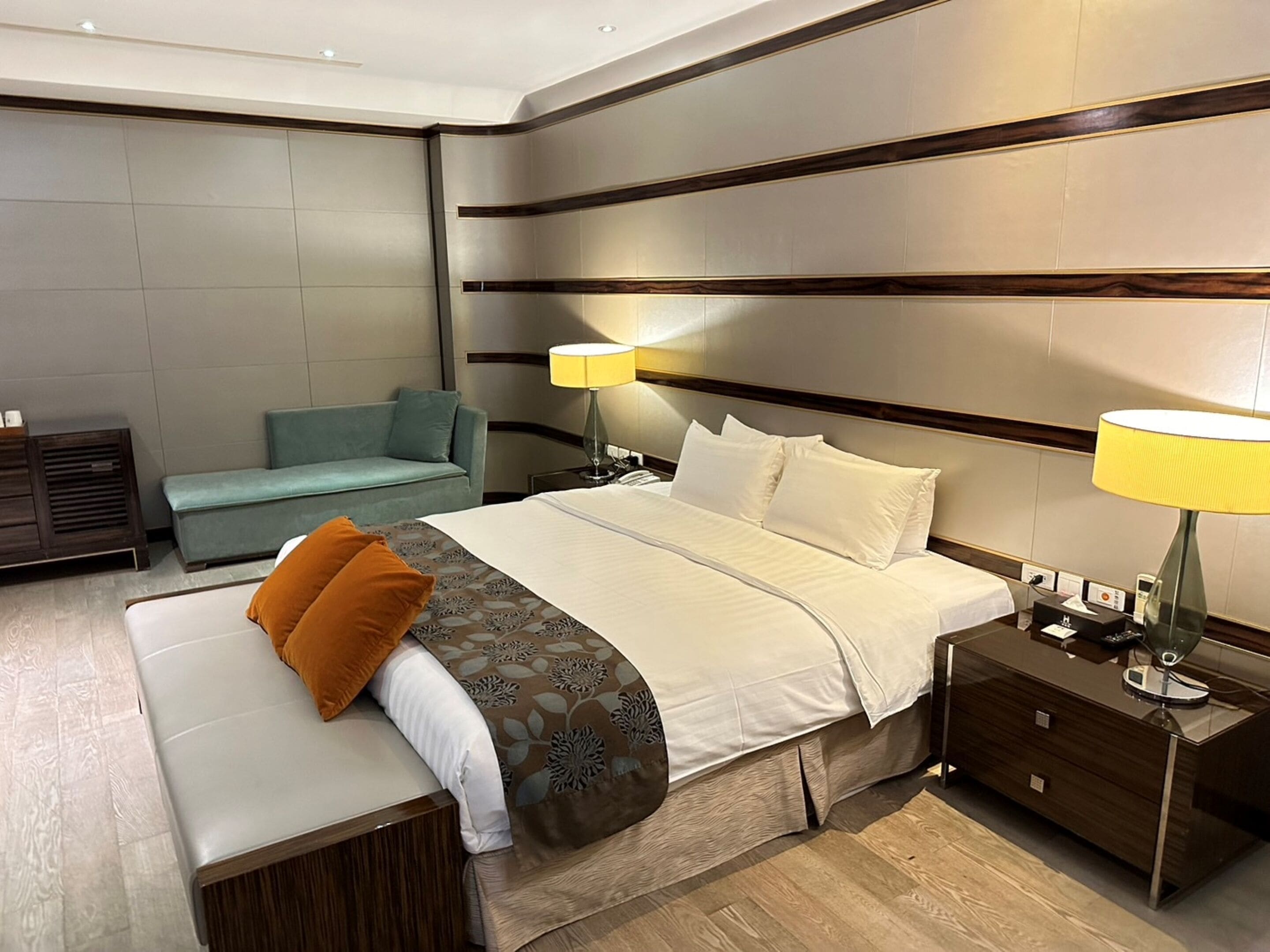 Una habitación de hotel moderna con una cama grande, mesitas de noche, un sofá y un escritorio.