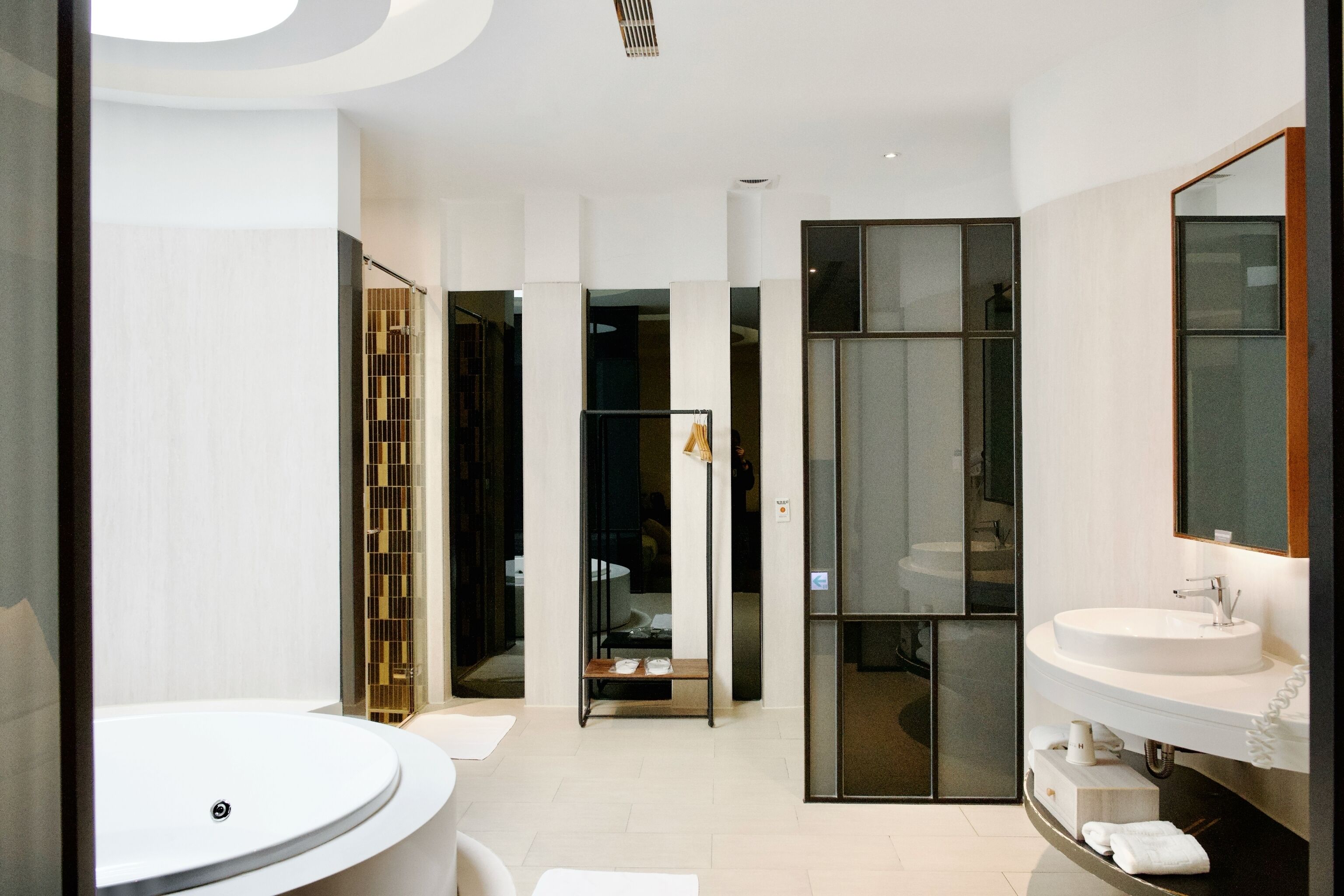 A modern bathroom with a round sink, a large mirror, and a glass shower enclosure.