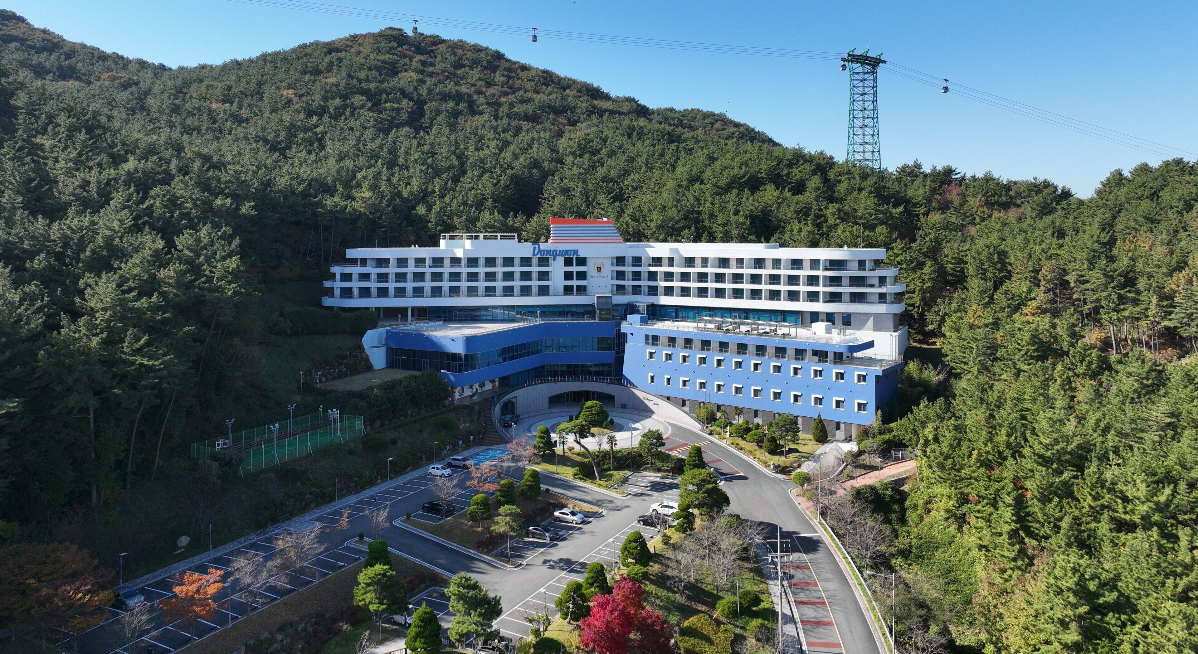 A modern hotel with a curved facade, multiple floors, and a parking lot.
