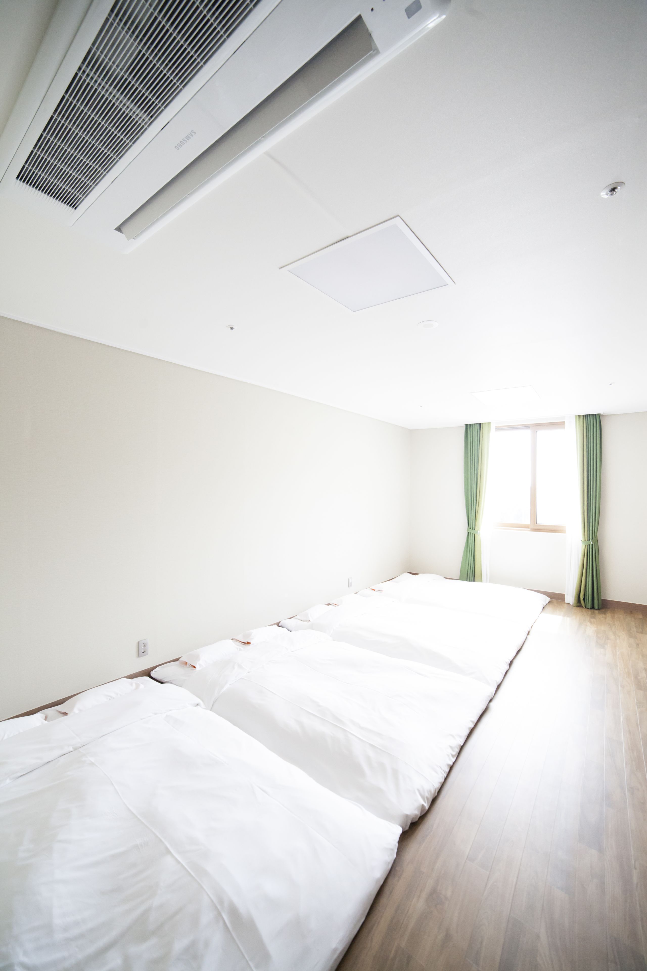 Une chambre dotée d’un grand lit, d’une fenêtre avec des rideaux et d’un appareil de climatisation.