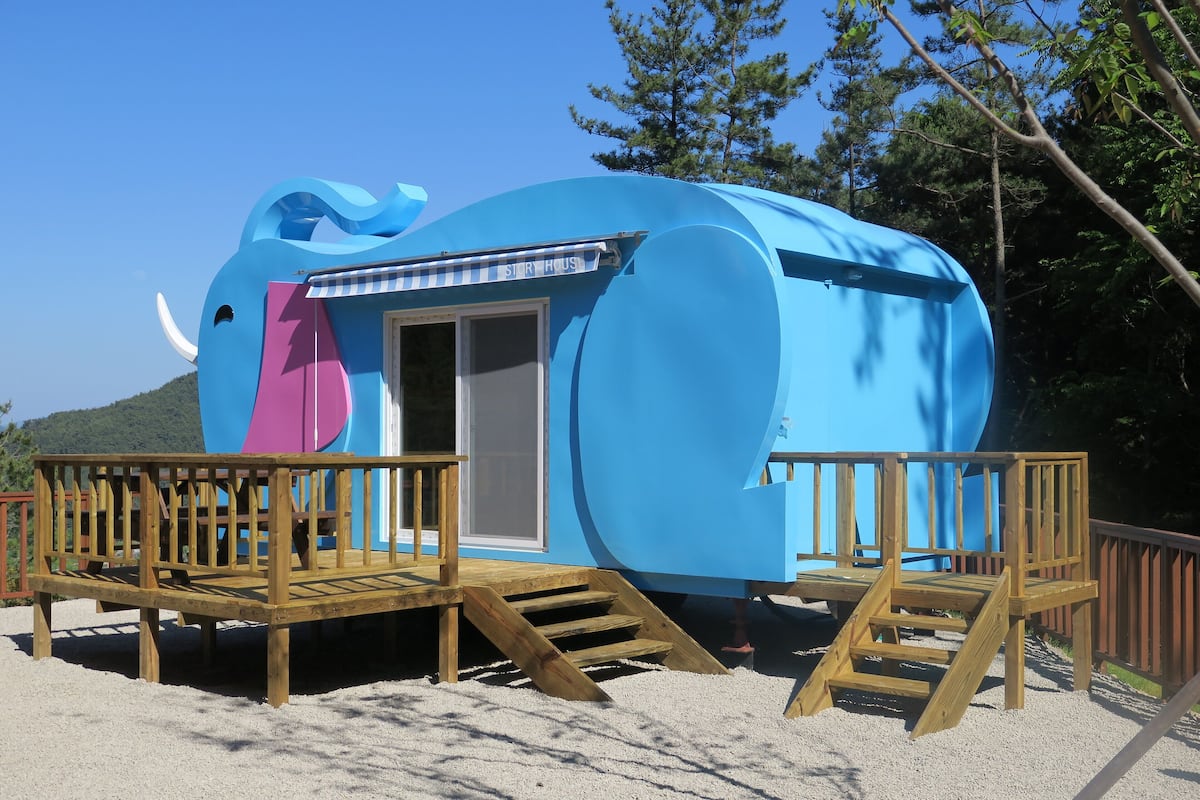A blue elephant-shaped building with a door and a small deck.