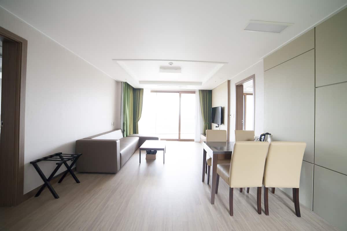 A modern living room with a sofa, coffee table, and dining area with chairs.