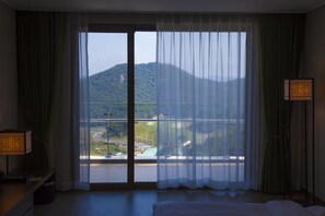 A hotel room with a large window, a bed, a nightstand, and a lamp. - Tongyeong Dongwon Resort & Youth Hostel (Tongyeong)
