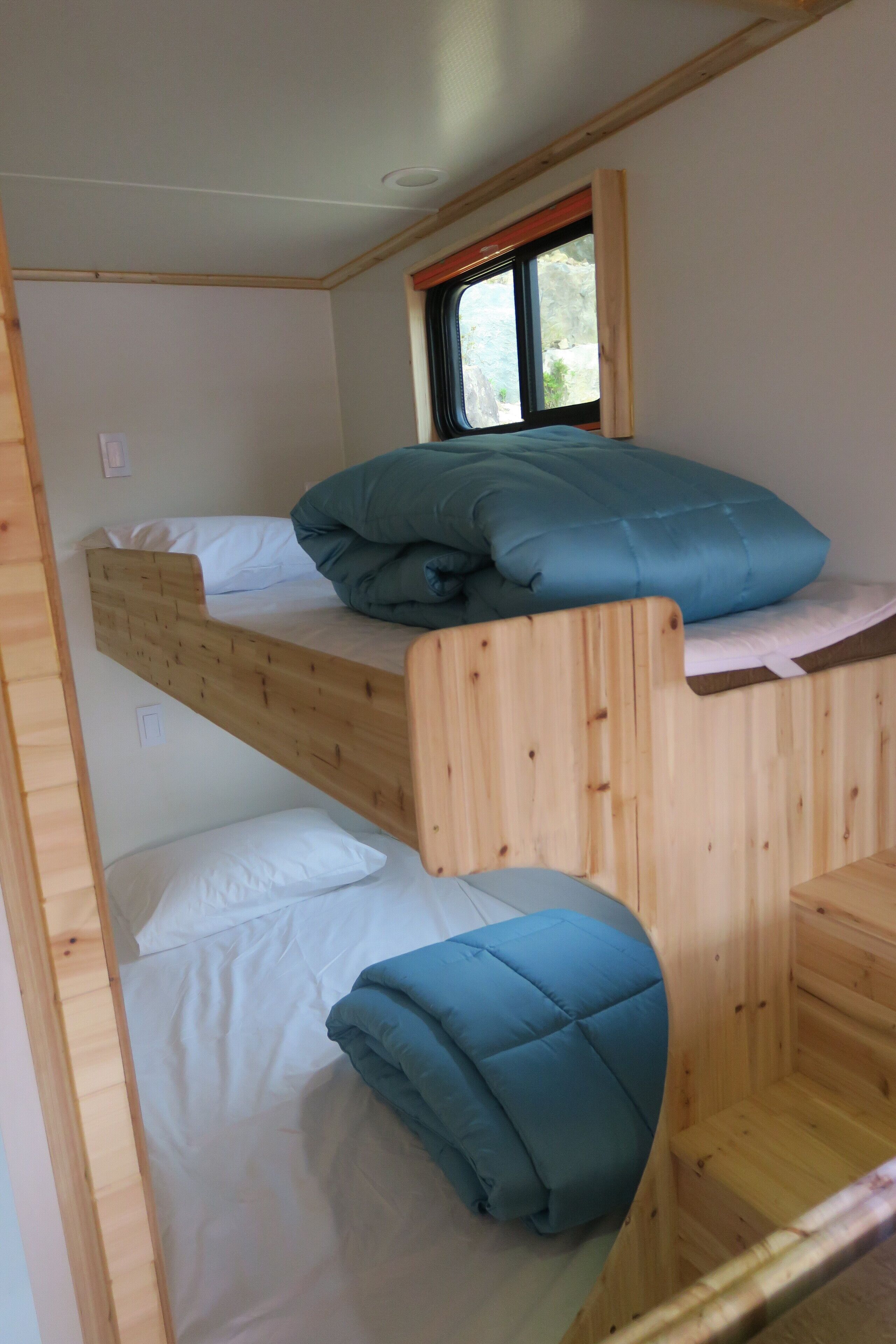 Una cama litera con dos niveles, cada uno con almohadas y cabecero de madera.
