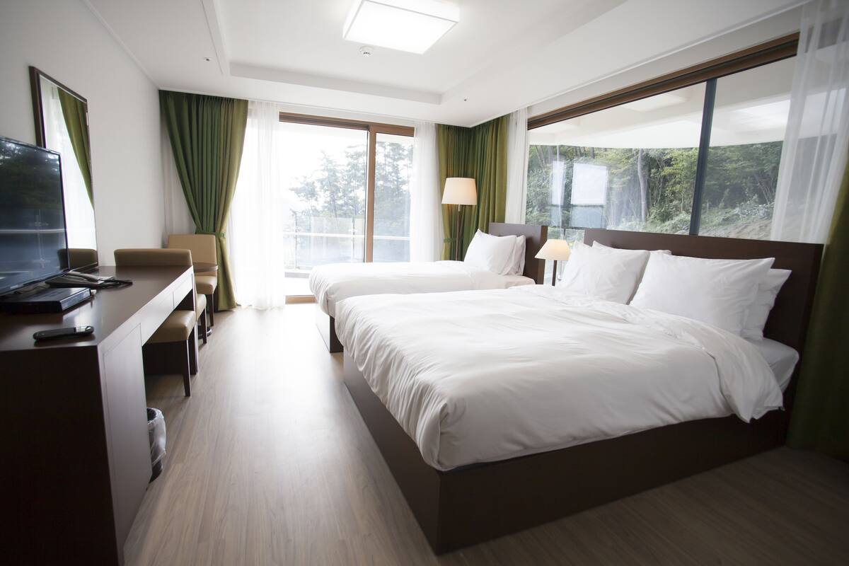 A hotel room with a bed, a desk with a computer, a chair, and a TV.