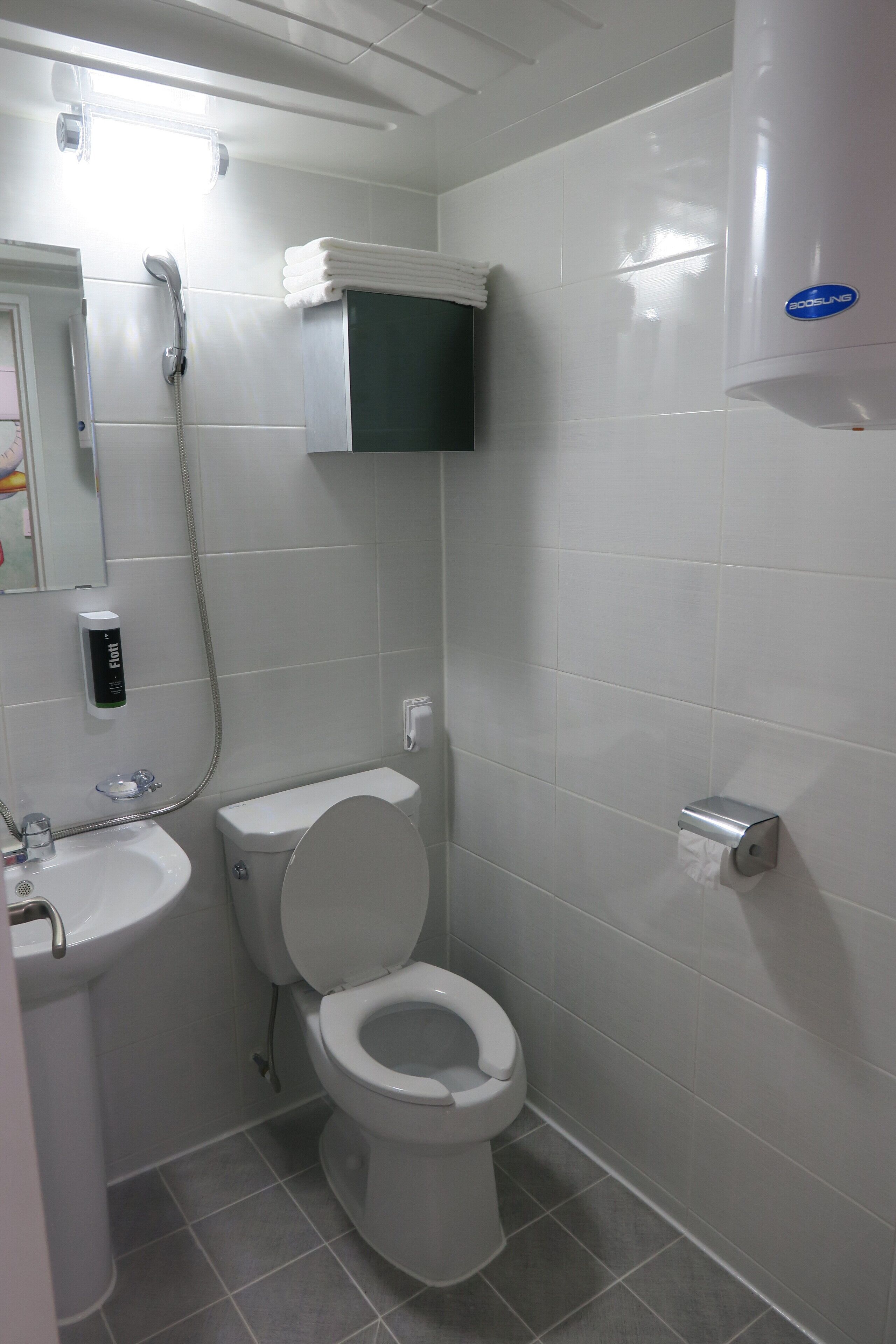 Ein kleines, sauberes Badezimmer mit Toilette, Waschbecken und einem Händetrockner.