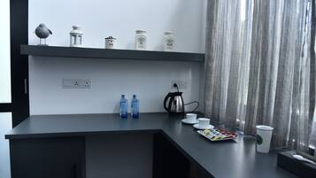 A modern kitchen with a dark countertop, a kettle, cups, and jars labeled tea and sugar.
