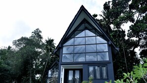 A modern two-story house with large windows and a triangular roof, surrounded by lush greenery. - The Country House (Galle)