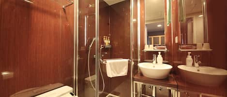 Un baño moderno con cabina de ducha de vidrio, un lavabo blanco y un espejo sobre el lavabo.