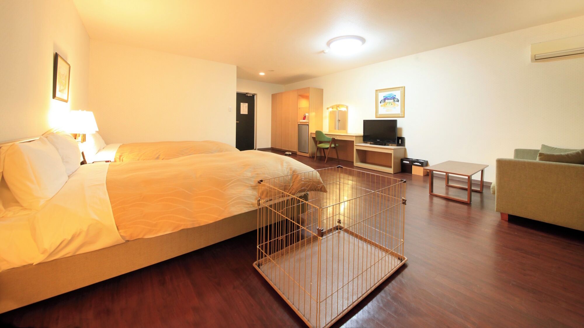 A hotel room with a bed, a desk, a television, a sofa, and a small table.