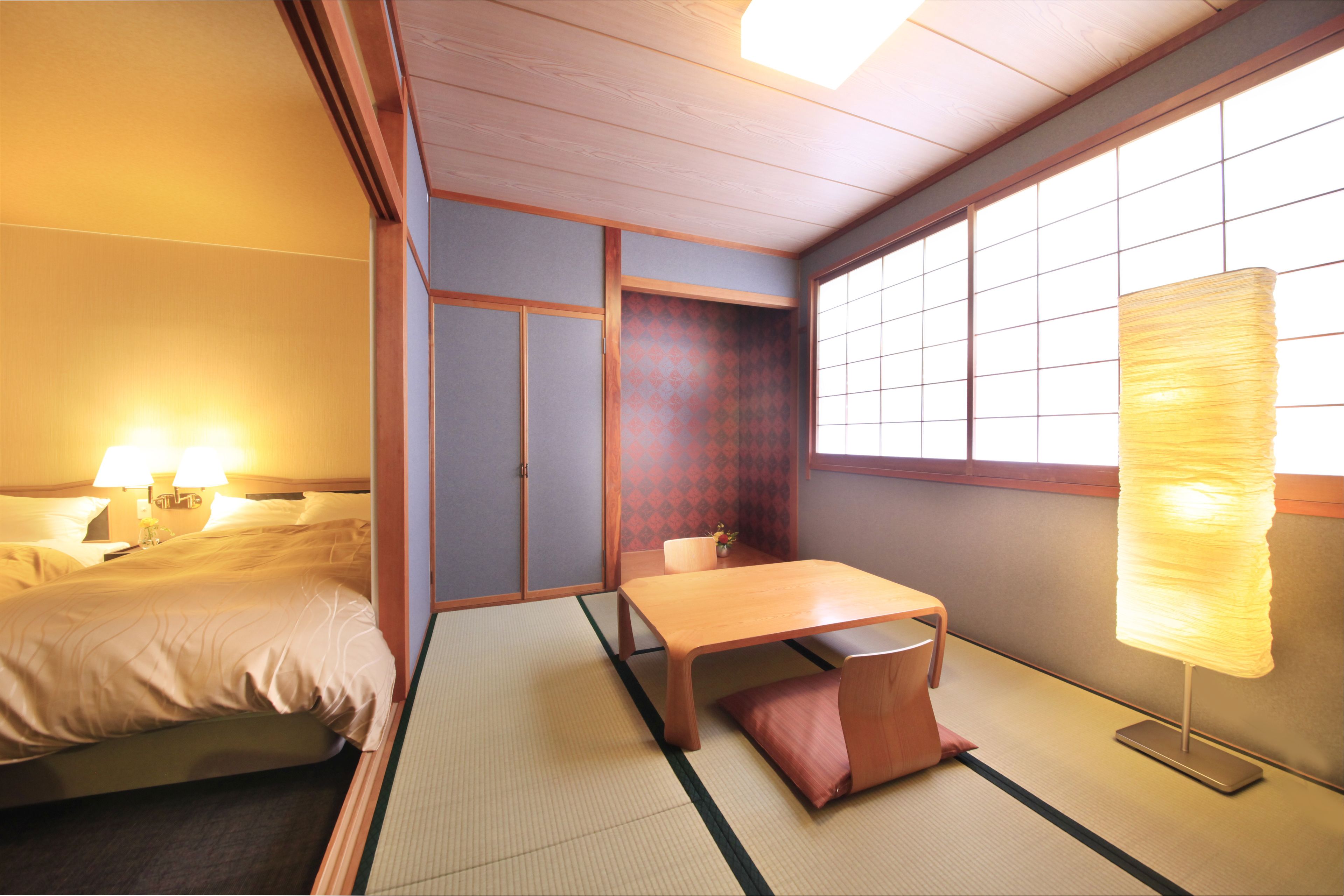 Una habitación japonesa tradicional con suelo de tatami, una mesa de madera baja, un banco acolchado, un biombos shoji y un farolillo de papel colgante.