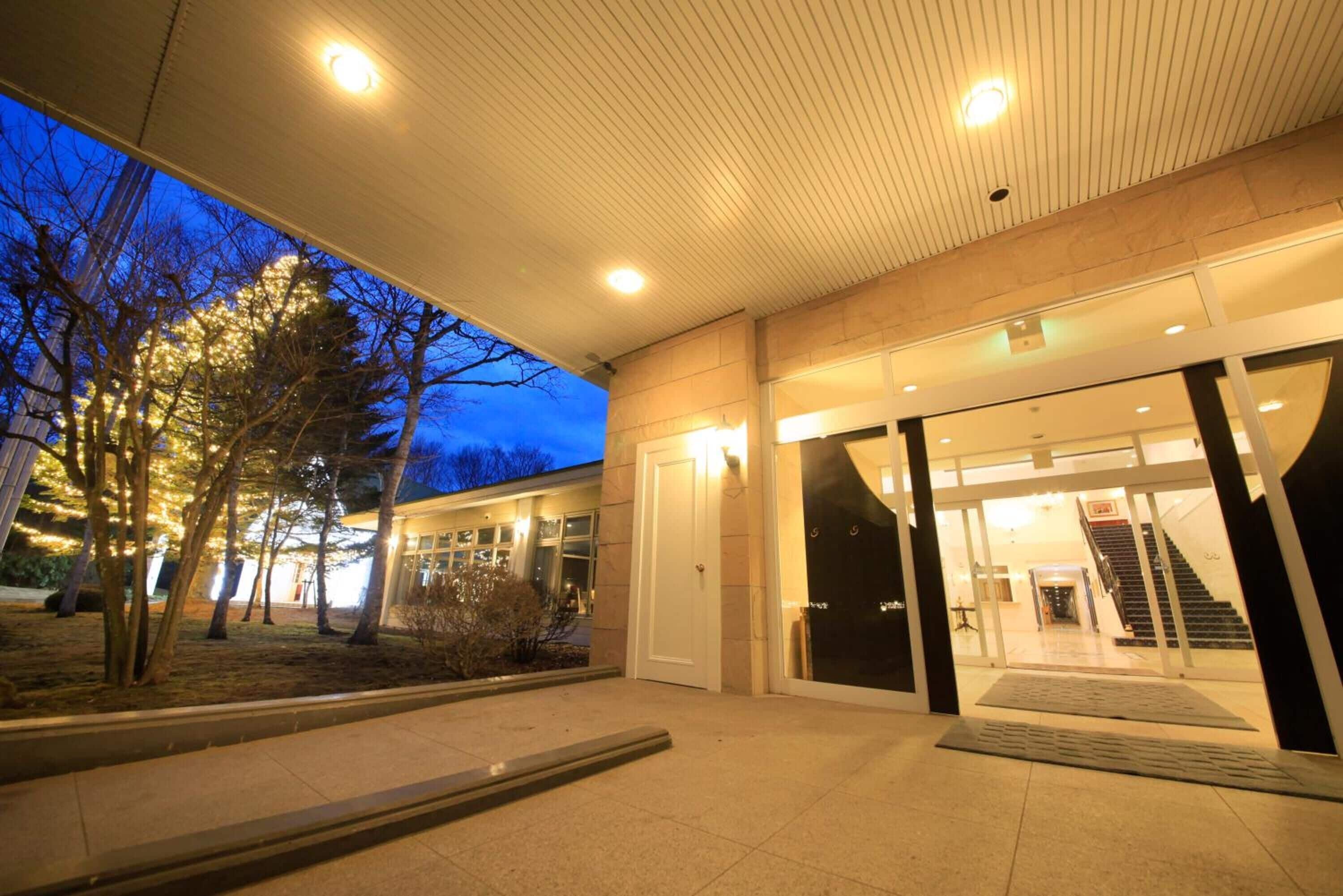 A modern building entrance with a covered walkway, glass doors, and a staircase leading inside.