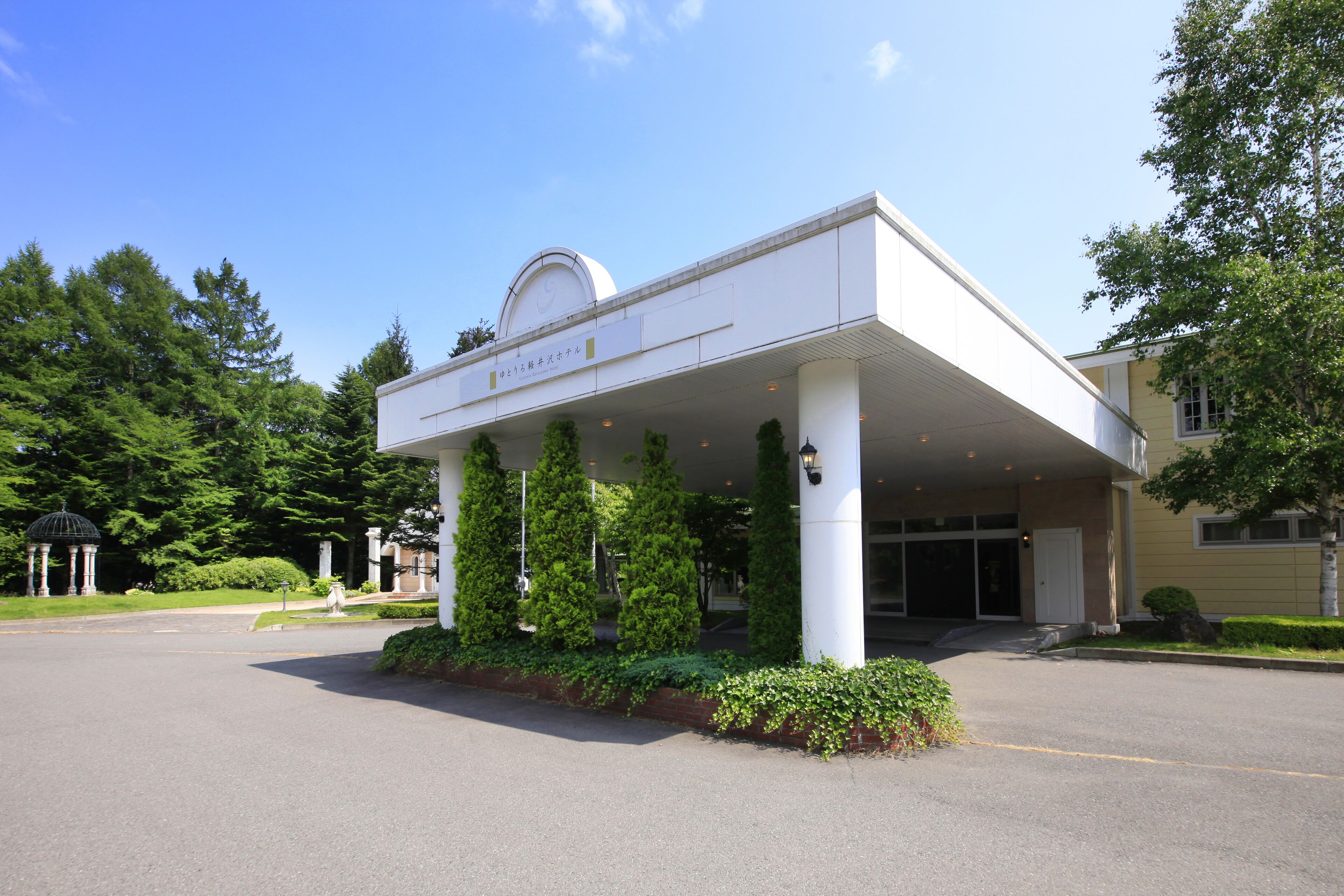 A hotel entrance with a covered area supported by columns, a dome-shaped roof, and a sign with Japanese characters.