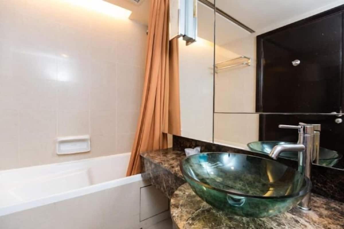 Een aparte badkuip en douche, een diep bad, een regendouche
