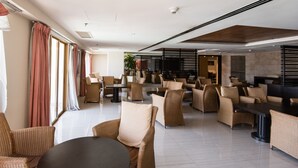 A spacious indoor area with multiple seating arrangements, including round tables and sofas, and large windows allowing natural light. - W Studio Resort Suites at Pyramid Tower (Petaling Jaya)