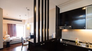 A modern kitchen with black cabinets, a stainless steel sink, and a dining area with a table and chairs. - W Studio Resort Suites at Pyramid Tower (Petaling Jaya)