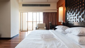 A hotel room with a large bed, a chair, a desk, and a view of the outside through a large window. - W Studio Resort Suites at Pyramid Tower (Petaling Jaya)
