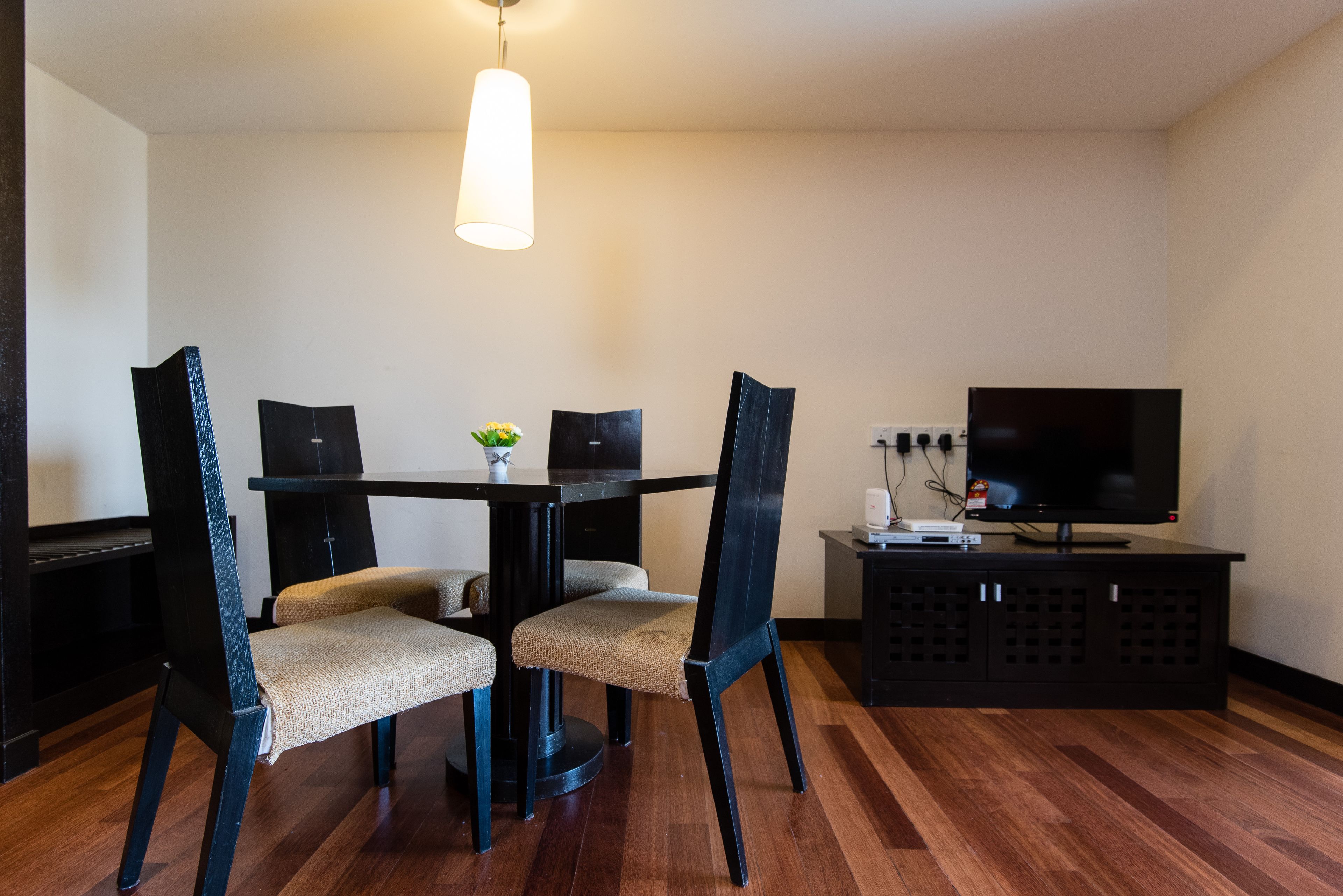 Un comedor con una mesa, cuatro sillas, un televisor y un armario.