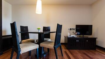 Un comedor con una mesa, cuatro sillas, un televisor y un armario.