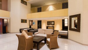 A spacious lobby with a high ceiling, a seating area with wicker furniture, a fireplace, and a large mirror on the wall. - W Studio Resort Suites at Pyramid Tower (Petaling Jaya)