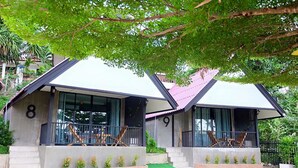 Deux petites maisons modernes, dotées de grandes fenêtres et d’un balcon, portant les numéros 8 et 9, et entourées de verdure.