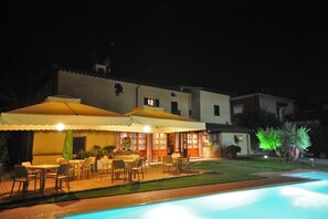 Una piscina al aire libre, sombrillas, sillones reclinables de piscina