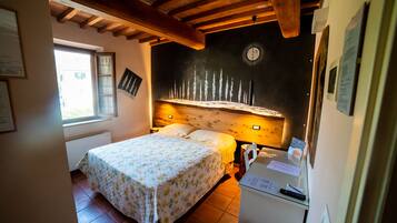 Une chambre à coucher avec un lit, une table de chevet, une horloge et une fenêtre.