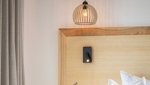A neatly made bed with white linens, a wooden headboard, and a bedside table with a small decorative item. - Hotel Filser (Fuessen)