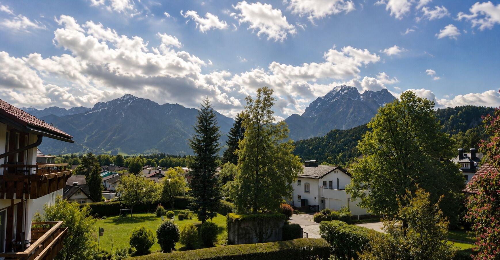 A residential area with houses, a well-maintained lawn, and mountains in the background.
