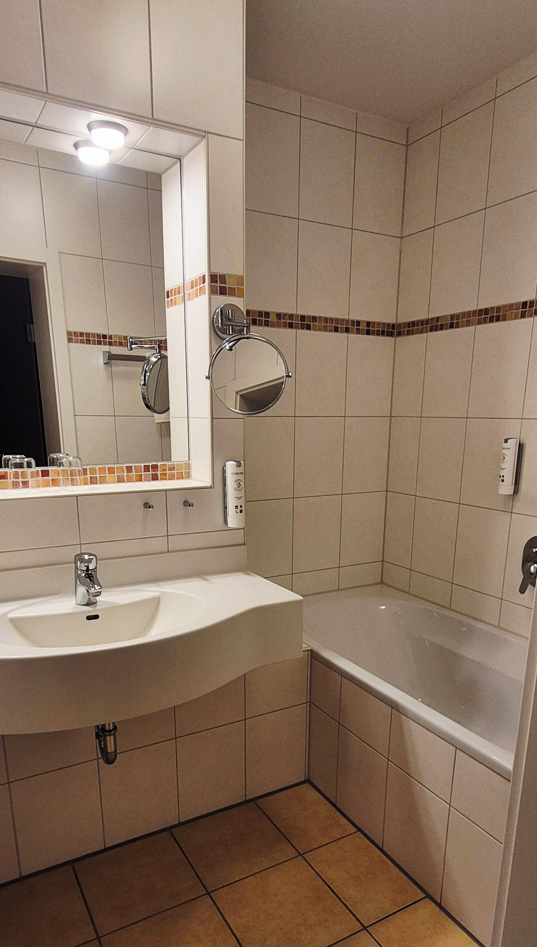 A bathroom with a sink, mirror, and bathtub.