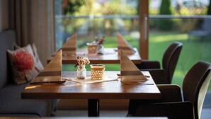 A dining table with two triangular placemats, a glass vase with dried flowers, and a woven basket. - Hotel Filser (Fuessen)