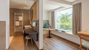 A modern bathroom with a shower, toilet, and a vanity with a mirror. - Hotel Filser (Fuessen)