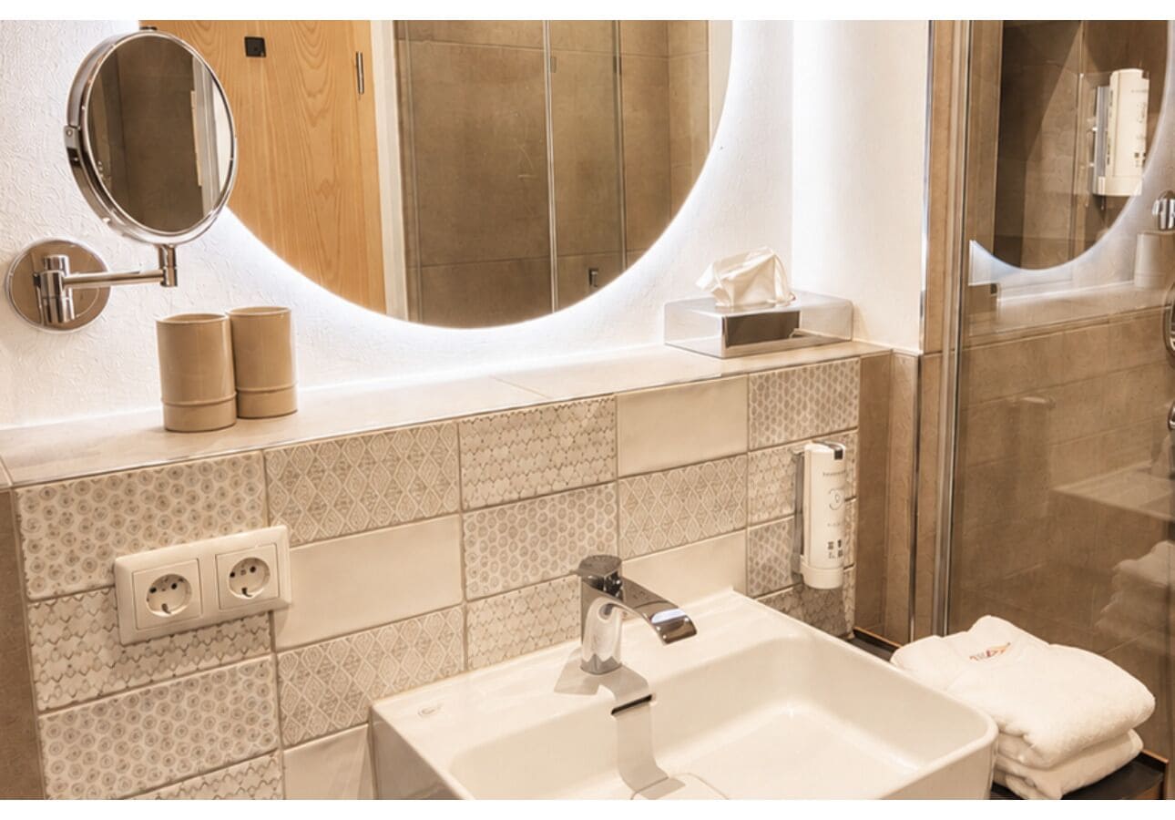 A bathroom with a sink, mirror, towel rack, and shower.